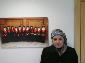 Aida Ismail vor dem Foto der Abschluss-Zeremonie eines älteren Ausbildungs-Jahrgangs.