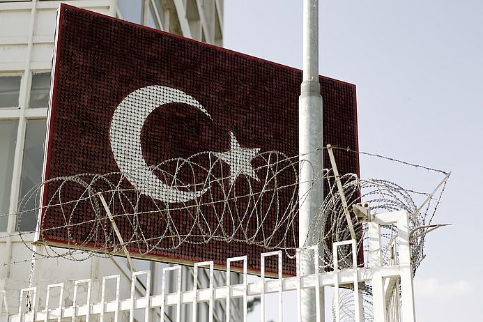 Das Bild zeigt eine türkische Flagge und Stacheldraht. 