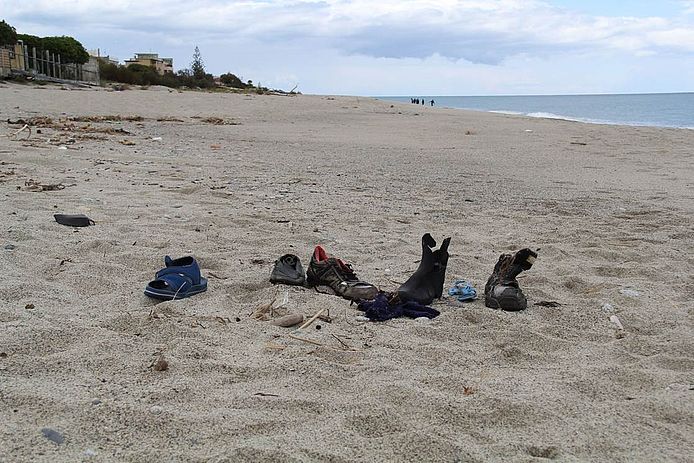 Das Bild zeigt Schuhe im Sand an einem Strand.