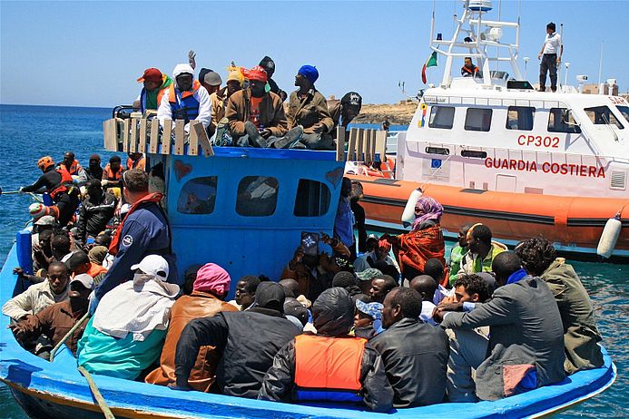 Ein Boot mit Flüchtlingen und die Küstenwache bei Lampedusa.