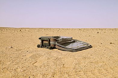 Ein Koffer liegt in der Wüste