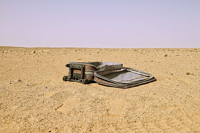 Ein Koffer liegt in der Wüste