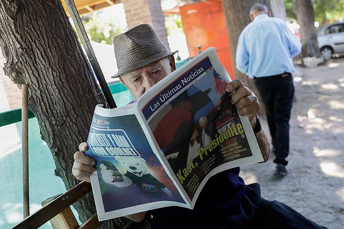 Ein älterer Mann liest eine Zeitung mit der Schlagzeile "Kast, Presidente"