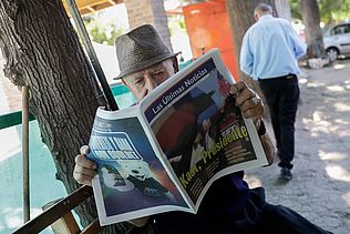 Ein älterer Mann liest eine Zeitung mit der Schlagzeile "Kast, Presidente"