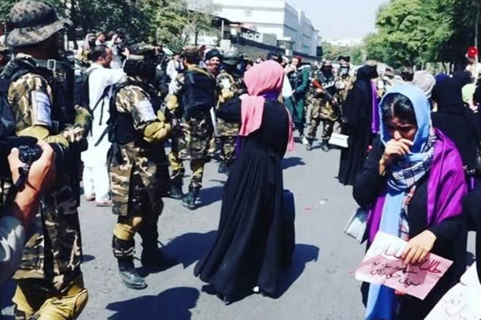 Straßenszene in Afghanistan mit Frauen und Soldaten.