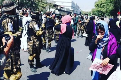 Straßenszene in Afghanistan mit Frauen und Soldaten.