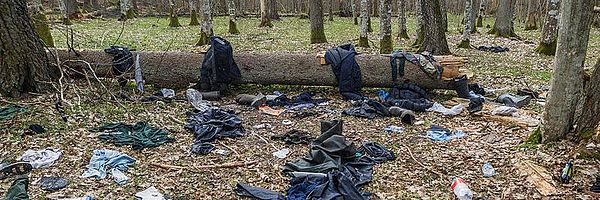 Kleidung liegt verstreut auf einer Lichtung.