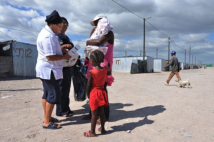 Eine südafrikanische Gesundheitshelferin befragt Bewohnerinnen zu ihren Lebensverhältnissen im Township.