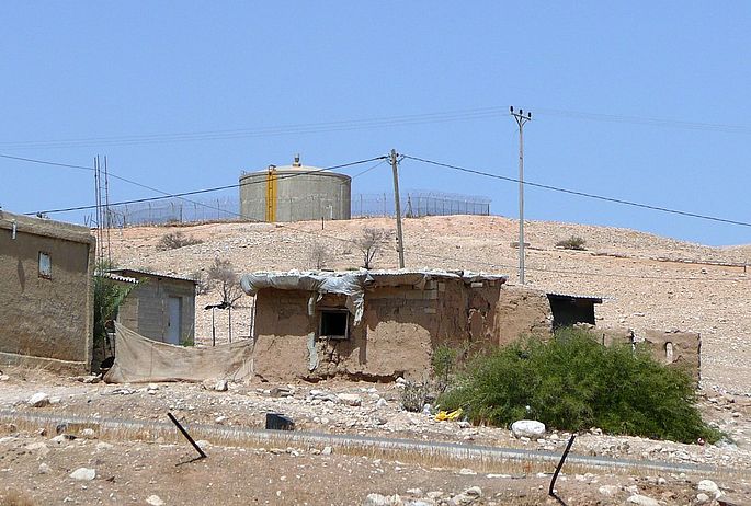 Alltag im Jordantal. Der Wassertank ist mit Stacheldraht umzäunt und nur für die Siedler da, unten die Behausung einer armen Familie in Jiftlik.