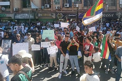 Menschen protestieren mit Schildern und Fahnen in Suweida.