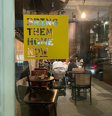 "Bring Them Home Now" steht an einer Glasscheibe.